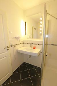 bagno bianco con lavandino e specchio di Villa Lena - Ferienwohnung 03 mit Balkon a Ostseebad Sellin