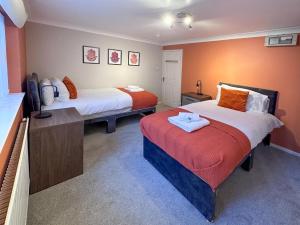 Habitación con 2 camas y paredes de color naranja. en BLUNSDON LODGE - Spacious Bungalow, High Speed Wi-Fi, Free Private Parking, Garden, en Swindon