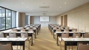 una sala de conferencias con mesas, sillas y una pantalla en neera retreat hotel, en Nakhon Pathom