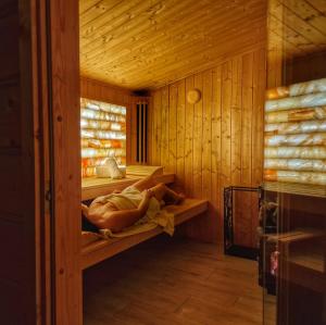 a woman laying on a shelf in a sauna at LK Resort Łapsze domy z prywatną balią i sauną in Łapsze Niżne