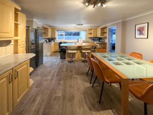 a kitchen with wooden cabinets and a table and chairs at BLUNSDON LODGE - Spacious Bungalow, High Speed Wi-Fi, Free Private Parking, Garden in Swindon
