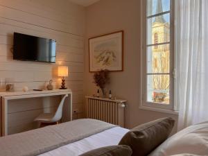 1 dormitorio con cama, escritorio y ventana en Le Chat Botté en Saint-Clément-des-Baleines