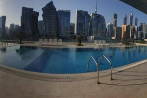 a large swimming pool with a city skyline in the background at Large cozy Studio(Hamilton Residency) in Dubai