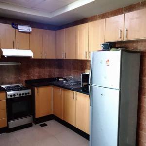 eine Küche mit einem weißen Kühlschrank und Holzschränken in der Unterkunft Large cozy Studio(Hamilton Residency) in Dubai