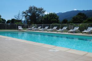 a swimming pool with lounge chairs and a fence at Residence Riviera in Porto-Vecchio