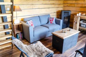 a living room with a blue couch and a table at La cabane du cerf et son sauna in Attre