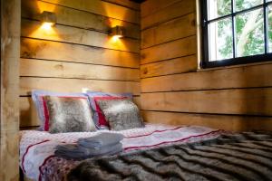 uma cama num quarto com paredes de madeira e uma janela em La cabane du cerf et son sauna em Attre