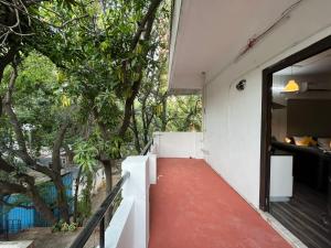 a house with a red floor and a balcony with trees at BedChambers Serviced Apartment, Jubilee Hills in Hyderabad