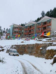 a car parked in front of a building in the snow at Satopanth The Auli Resort By Royal Collection Hotels in Joshīmath