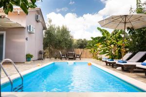 a pool with chairs and an umbrella next to a house at Villa Rigilis in Nydri