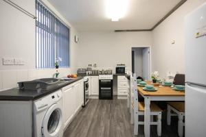 a kitchen with a washer and a table in it at Hömli*Close2City*LargeGroup*Wi-Fi* in Leicester