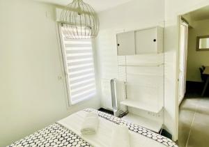 um quarto branco com uma cama e uma janela em Le Sunlight - T2 bord de mer, Parking em Palavas-les-Flots