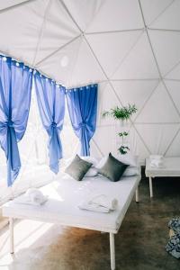 Sofá blanco en una habitación con cortinas azules en Family Fun Dome Glamping with Hotspring Pool (6 pax), en Lubo