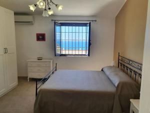 Appartamento - Plemmirio في سيراكوزا: غرفة نوم بسرير ونافذة وخزانة