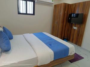 - une chambre avec un lit doté d'oreillers bleus et une télévision dans l'établissement HOTEL ROYAL GRAND, à Ahmedabad