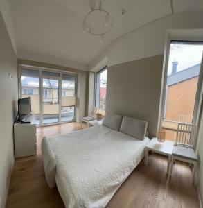 1 dormitorio con 1 cama blanca grande y ventanas grandes en Apartamentai Muziejaus g., en Birštonas