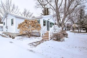 Une petite maison blanche dans la neige avec une pile de bûches dans l'établissement Green Lake Vacation Home with Screened Porch!, à Green Lake