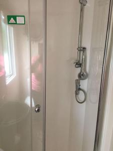 a shower in a bathroom with a glass door at Susie's Beautiful Caravan near the sea in Pwllheli
