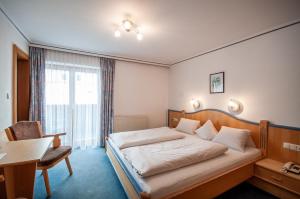 a hotel room with a bed and a desk and a chair at Frühstückspension Tannenhof in Kirchberg in Tirol