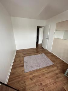 ein leeres Zimmer mit einem Teppich auf einem Holzboden in der Unterkunft Étoile en banlieue parisienne in Montigny-lès-Cormeilles