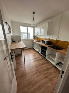eine Küche mit weißen Schränken und Holzböden in der Unterkunft Étoile en banlieue parisienne in Montigny-lès-Cormeilles