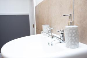 a bathroom sink with a soap dispenser on it at ST MARGARETS - Spacious Home, High Speed Wi-Fi, Free Parking, Garden in Swindon