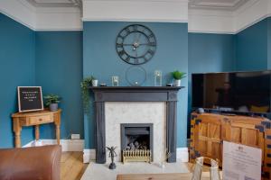 a living room with a fireplace and a clock on the wall at ST MARGARETS - Spacious Home, High Speed Wi-Fi, Free Parking, Garden in Swindon