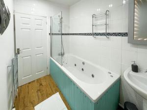 a bathroom with a tub and a sink at SHRIVENHAM - Spacious Home, High Speed Wi-Fi, Free Parking, Garden in Swindon