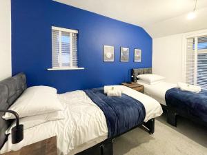 a bedroom with two beds and a blue wall at SHRIVENHAM - Spacious Home, High Speed Wi-Fi, Free Parking, Garden in Swindon