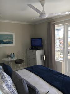 a bedroom with a bed and a tv and a window at Seaforth Suite in Simonʼs Town