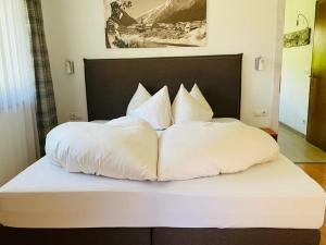 Una cama con sábanas blancas y almohadas. en Haus Schuchter, en Pfunds