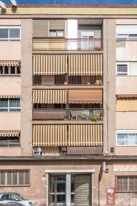 un edificio de apartamentos con un balcón con plantas. en Sunny rooms on Cabañal beach, en Valencia