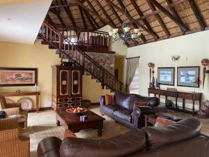 a living room with leather furniture and a staircase at Lodge on Watering Hole , Zebula in Mabula