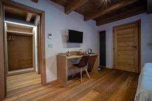 um quarto com uma secretária e uma televisão na parede em Fleur des neiges & Spa - Adults only em Ayas