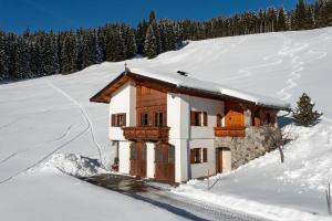 una pequeña casa en la nieve con nieve en Flecklhütte, en Hopfgarten im Brixental