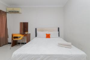 1 dormitorio con 1 cama blanca grande con almohada naranja en KoolKost near Tunjungan Plaza, en Surabaya