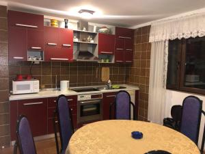 a kitchen with red cabinets and a table with chairs at Vila Bojana in Gornji Milanovac
