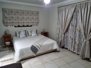 1 dormitorio con 1 cama blanca grande con cortinas en La Maison on Vaal Bed and Breakfast, en Denysville