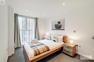 um quarto com uma cama e uma grande janela em Fully Serviced Two Bed Apartment by ExCeL & O2 em Londres