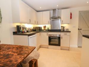 a kitchen with white cabinets and a wooden table at Cudfan Fach in Pwllheli