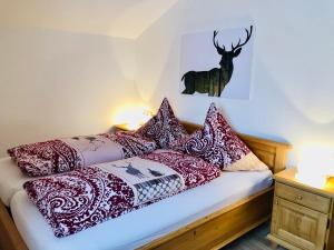 a bed with red and white pillows and a deer on the wall at Schmölz Robert in Rieden am Forggensee