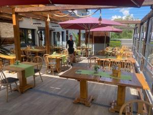 a man standing on a patio with tables and umbrellas at Hohennneuffen Blick in Beuren