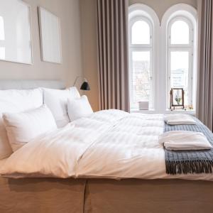 a bedroom with a large white bed with two windows at The Duxiana Malmö in Malmö