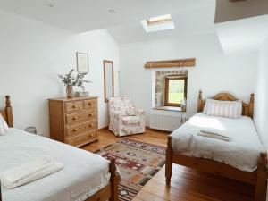 a bedroom with two beds and a dresser and a chair at L'ancien Relais de Poste*** in Saint-Dier-dʼAuvergne