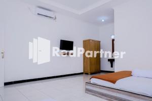 1 dormitorio con 1 cama y TV en la pared en Villa Ikhbar Ciletuh RedPartner, en Cilowa