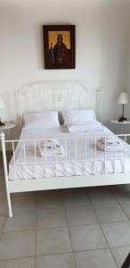 a white bed in a bedroom with a painting on the wall at Sea front Villas Danezis in Symi