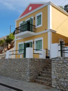a yellow house on top of a stone wall at Sea front Villas Danezis in Symi