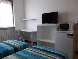 um quarto com uma cama e uma secretária com uma televisão em La Locanda Di Perico Paola em Veruno
