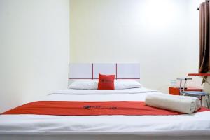 uma grande cama branca com um cobertor vermelho em RedDoorz at Buah Batu 5 em Bandung