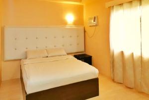 um pequeno quarto com uma cama branca e uma janela em RedDoorz @ Jackie’s Hotel & Restaurant em Ipil